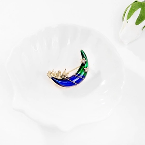 Détail d'une broche croissant de lune en émail bleu avec silhouette de ville dorée