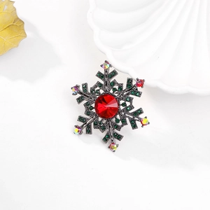 Detail shot of a snowflake brooch featuring a large red crystal and green rhinestones