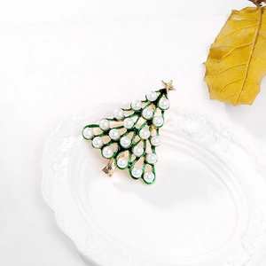 Detailed close-up of a Christmas tree brooch with green enamel and white pearls
