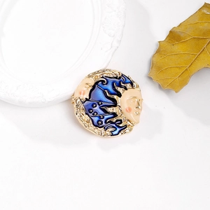 Detail of sun and moon round brooch with blue enamel and gold stars on a white tray