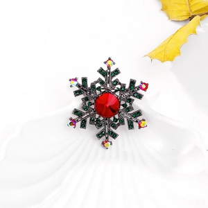 Macro detail of vintage snowflake brooch with red centerpiece and green rhinestones