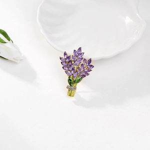 Dettaglio di spilla a lavanda in cristallo con pietre viola e steli dorati su vassoio