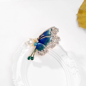 Macro view of butterfly brooch with colorful enamel, rhinestones and a large pearl inlay