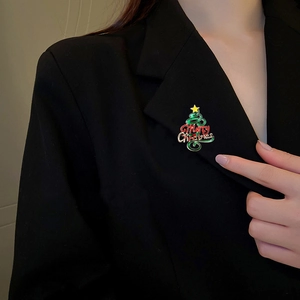 Broche sapin de Noël en émail coloré avec strass portée sur un revers de veste