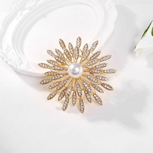 Golden sun flower brooch with pearl and sparkling crystals on an elegant white surface