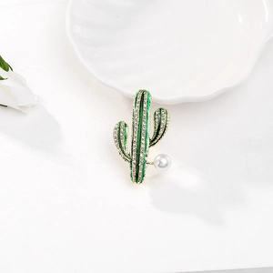 Dettaglio di una spilla a cactus in smalto verde con strass bianchi e una perla