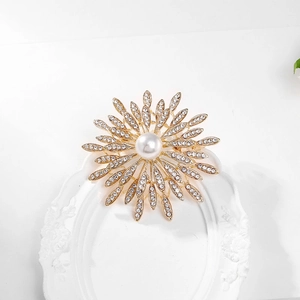 Detailed close-up of golden sunflower brooch with sparkling crystals and pearl center
