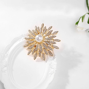 Close-up of golden sunflower brooch with a white pearl and sparkling crystals on a tray