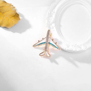 Elegant airplane brooch with white enamel and rhinestones on a minimalist white surface