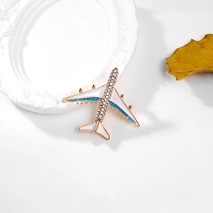 Detailed close-up of a white enamel airplane brooch with sparkling rhinestones and blue lines