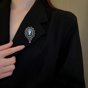 Detail of vintage cameo brooch with blue silhouette and crystal tassels on black blazer