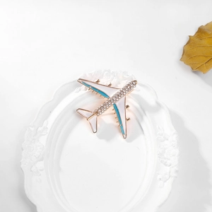 Detail of creative airplane brooch with sparkling rhinestones and white enamel finish