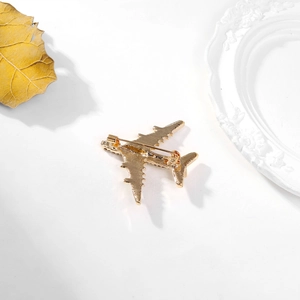 Detail view of the golden airplane brooch back featuring textured finish and safety pin