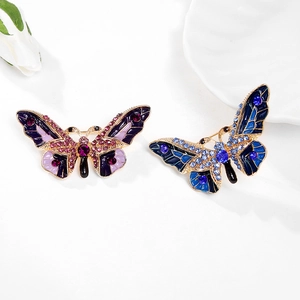 Broches papillons élégantes avec cristaux violets et bleus sur une assiette blanche