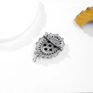 Reverse view of vintage silver brooch featuring a classic pin fastener and teardrop pendant