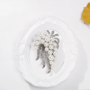 Silver grape cluster brooch featuring white pearls and sparkling rhinestones on an elegant tray