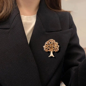 Broche arbre dorée avec strass ambrés fixée sur le revers d'un blazer noir pour femme
