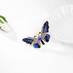 Macro d'une broche papillon en émail bleu avec cristaux et cadre en métal doré