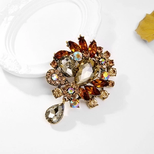 Vintage floral crystal brooch with amber rhinestones and teardrop pendant on white
