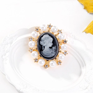 Vintage Victorian cameo brooch with pearls and crystals on a white ceramic plate