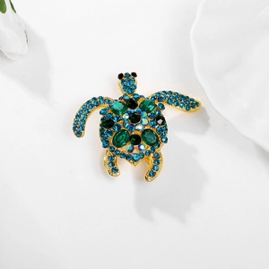 Prachtige schildpadbroche met groene edelsteen en blauwe kristallen op gouden legering