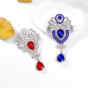 Baroque zinc alloy brooches with vibrant red and blue crystals on a white ceramic tray
