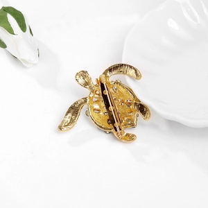 Detail van de achterkant van een gouden schildpadspeld met naaldsluiting en metaal
