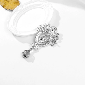 Detail of vintage silver zinc alloy brooch with sparkling rhinestones and teardrop pendant