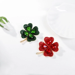 Detail of clover brooches with rhinestones and drop-shaped crystals on a white shell tray