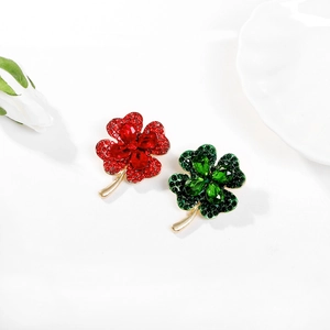 Detailed view of two four-leaf clover brooches in red and green with crystal pave