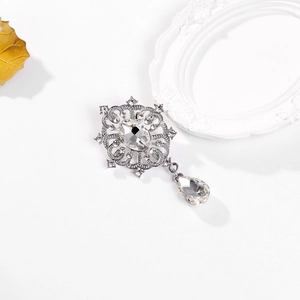 Detailansicht der silbernen Blumenbrosche mit Kristallanhänger und Strass auf weißem Grund