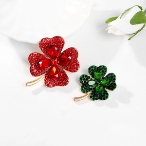 Macro detail of red and green clover brooches with rhinestones and gold alloy stems