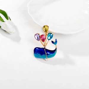Detail of blue whale brooch featuring colorful teardrop crystals and gold finish