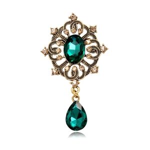 Vintage-Goldbrosche mit smaragdgrünen Edelsteinen und Champagner-Strass auf weißem Grund