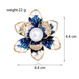 Détail de la broche fleur avec émail bleu, strass pavés et une perle blanche centrale