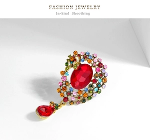 Vue détaillée d'une broche fleur vintage avec strass multicolores et pendentif rouge