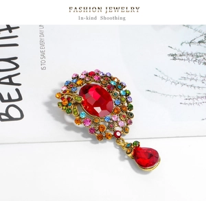 Détail de la broche vintage dorée avec cristaux colorés et pendentif goutte rouge