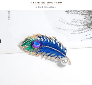 Detailed close-up of peacock feather brooch with blue enamel, crystals and white pearl