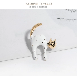 Detailansicht einer Katzenbrosche mit weißer Emaille, schwarzen Punkten und Goldfinish