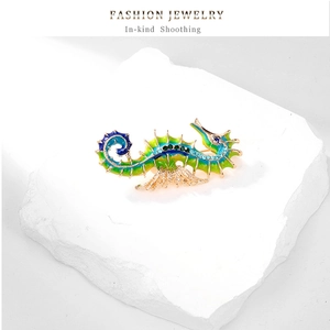 Detail of enamel seahorse brooch with green-blue gradient and crystals on stone