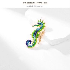 Macro shot of seahorse brooch with green-blue gradient enamel and inlaid rhinestones
