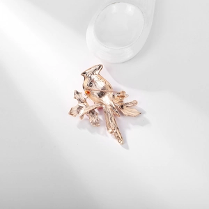 Elegant rose gold bird brooch on a branch with detailed back pin and metal texture