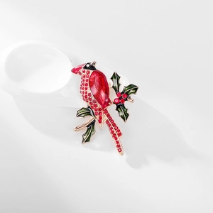 Macro shot of a red cardinal bird brooch with crystals on a holly branch detail
