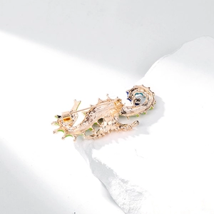 Enamel seahorse brooch with blue green details and gold plating on white stone