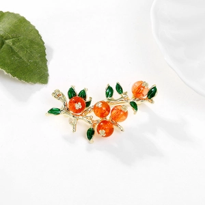 Spilla artistica a forma di cachi con rami dorati e perle arancioni su sfondo bianco