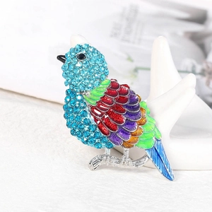 Spilla a forma di uccello con strass azzurri e ali smaltate su supporto bianco per gioielli