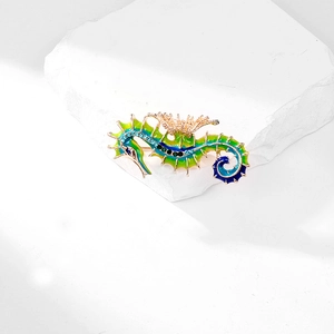 Enamel seahorse brooch in blue-green gradient with crystals on a white stone base