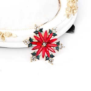 Détail d'une broche flocon de neige avec strass marquise rouges et feuilles en émail vert
