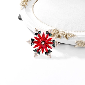 Broche flocon de neige de Noël avec cristaux rouges et feuilles vertes sur fond blanc