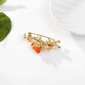 Spilla vintage a forma di cachi con perle arancioni su sfondo bianco testurizzato
